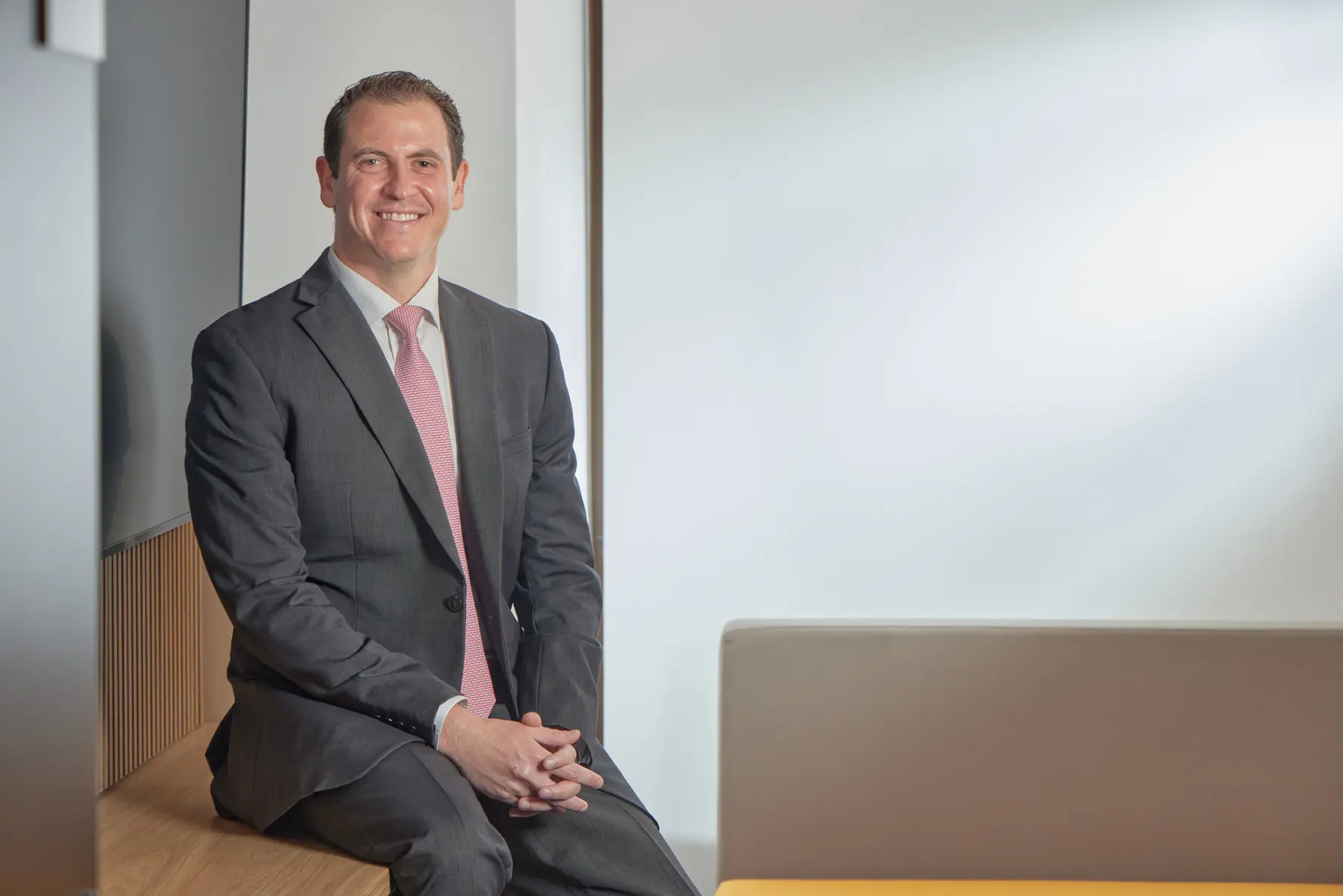 Daniel Rachman, CFO, em retrato executivo com traje formal em ambiente corporativo moderno e acolhedor