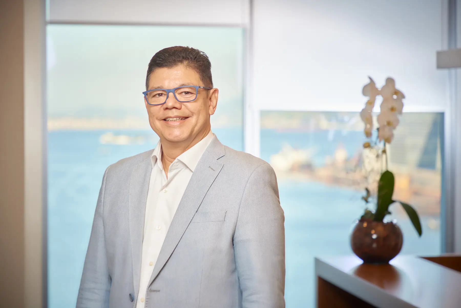 Executivo da Bradesco Seguros em retrato institucional com traje formal, diante de vista urbana e marítima