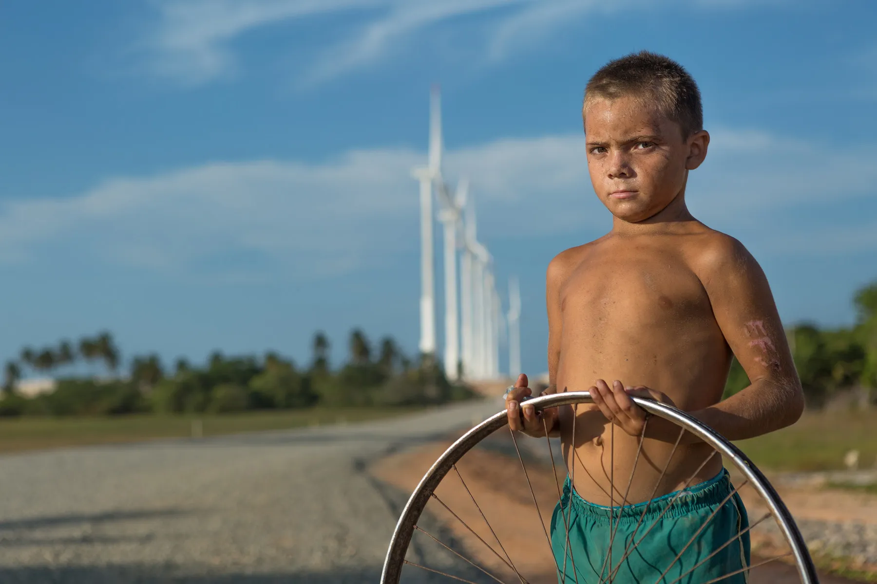 Criança em Icaraí de Amontada, Ceará, em território rural com turbinas eólicas ao fundo