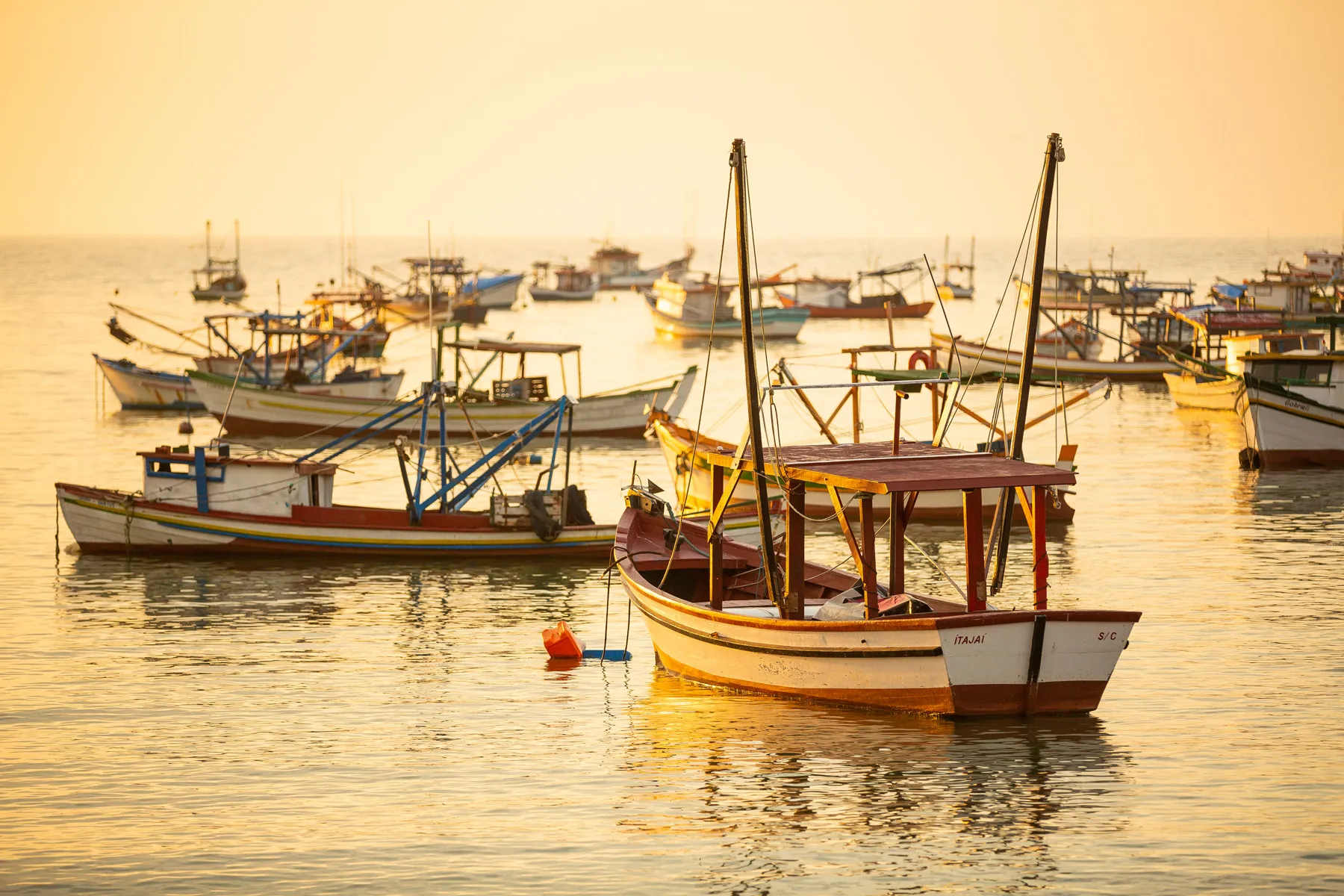 Barcos de pesca em Santa Catarina ao amanhecer, ligados a projeto social com imigrantes africanos