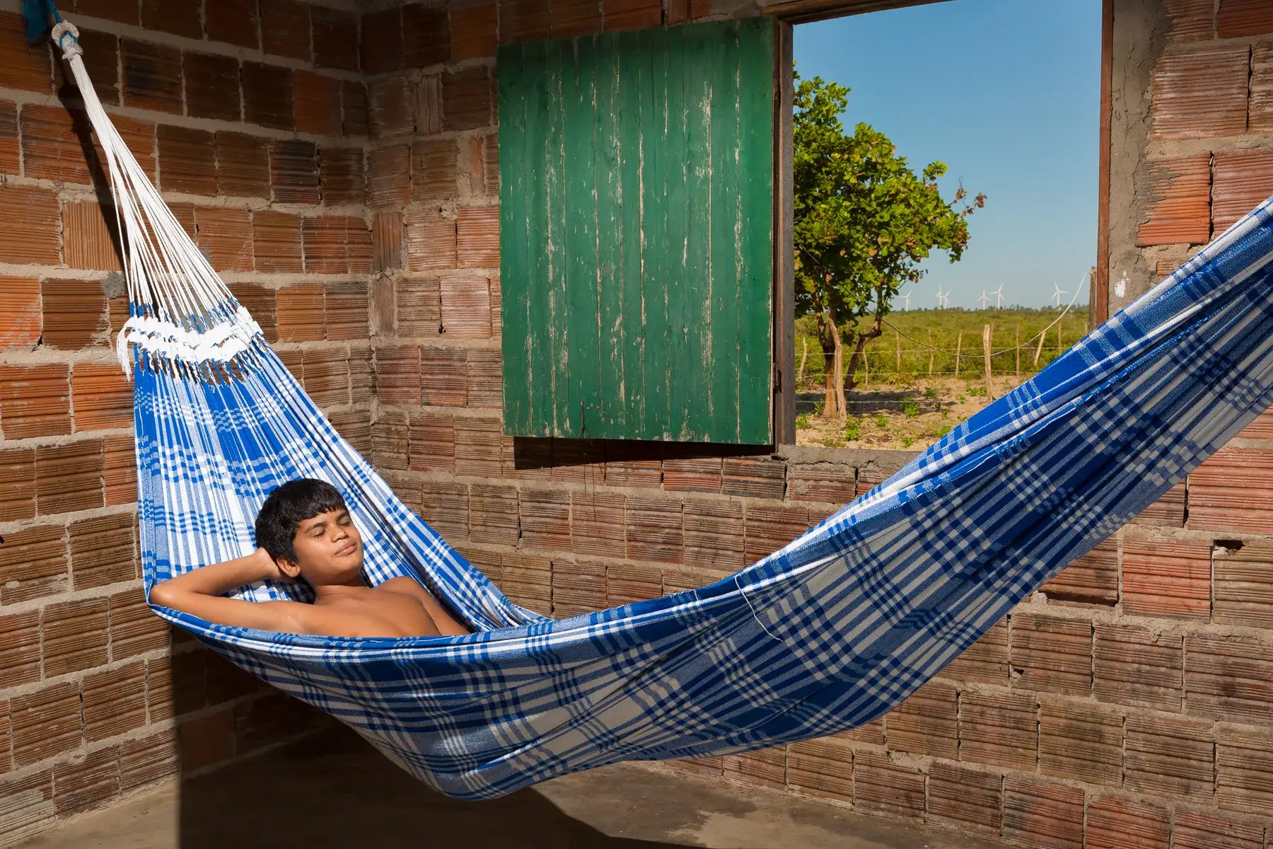 Jovem morador em casa rural no Complexo Eólico de Amontada, Ceará, com vista para o campo