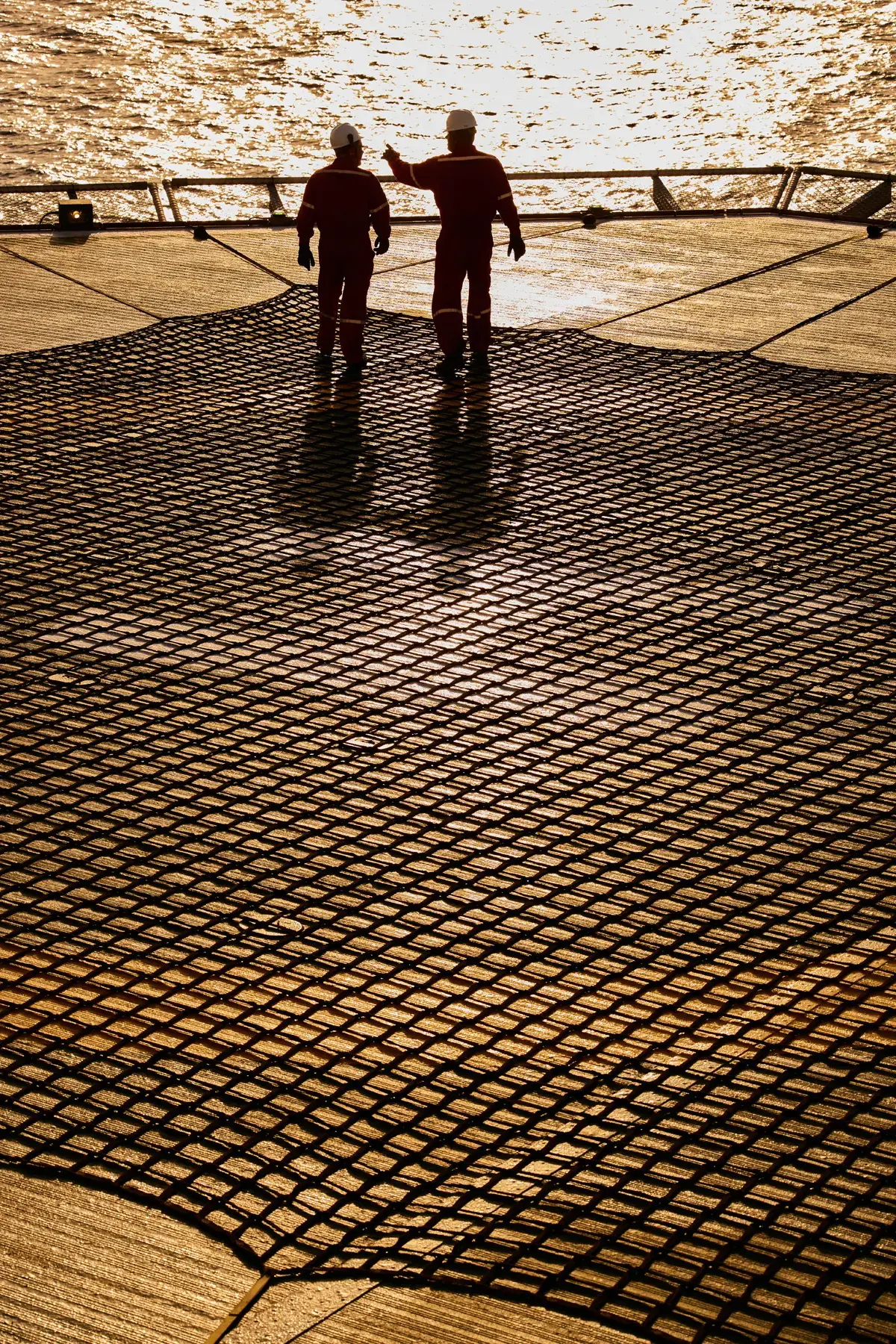 Trabalhadores sobre o heliponto de plataforma offshore da MODEC no Campo de Atlanta ao entardecer