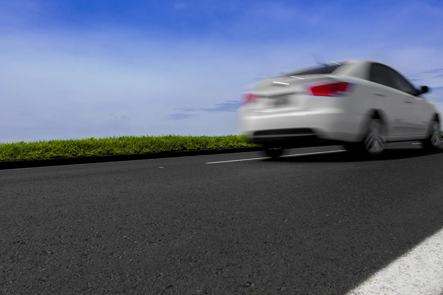 Carro em alta velocidade na Rodovia dos Tamoios, SP, com céu limpo e vegetação lateral