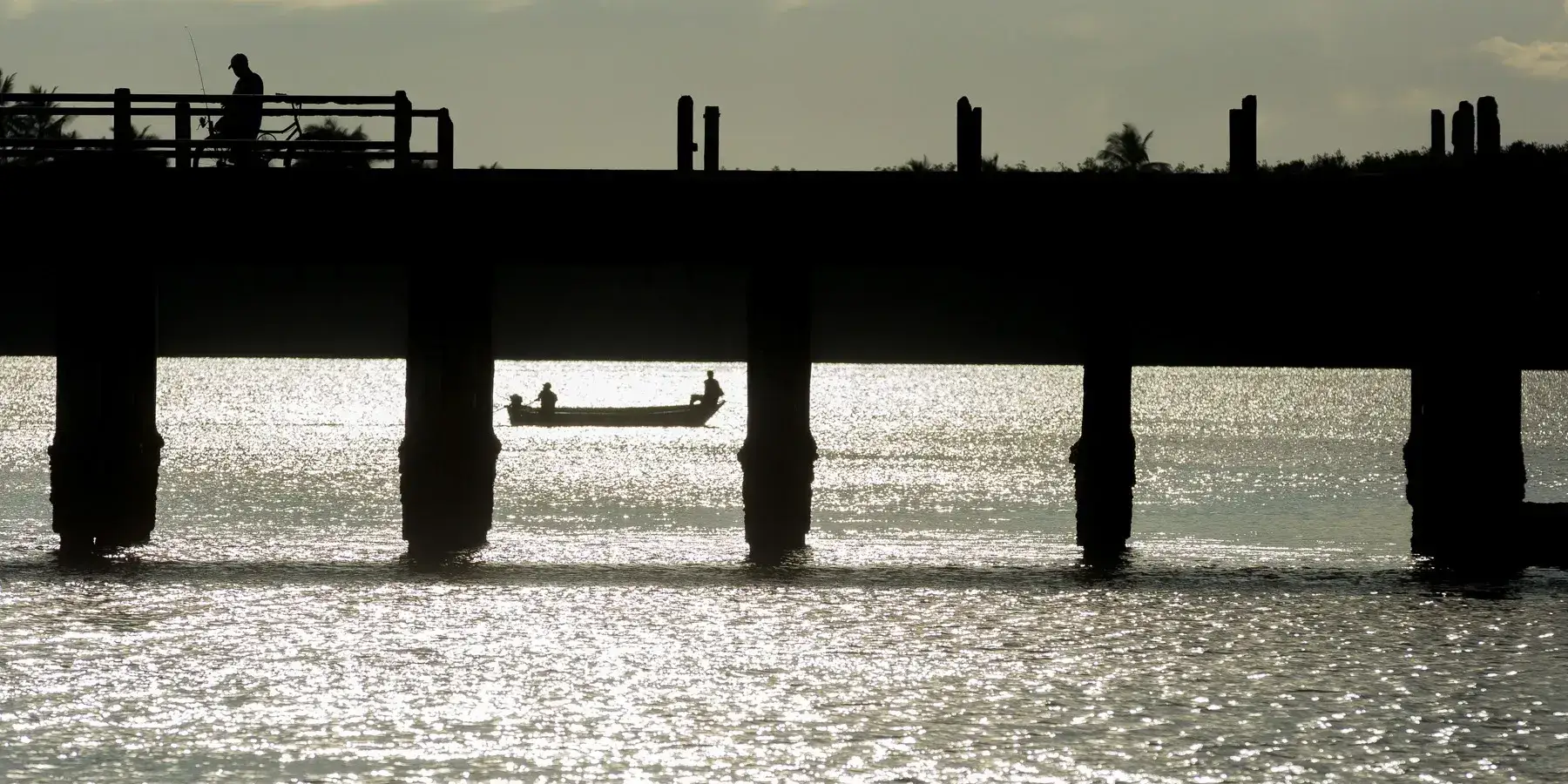 Ponte sobre corpo d’água no sul da Bahia com pessoas em embarcação e circulação comunitária