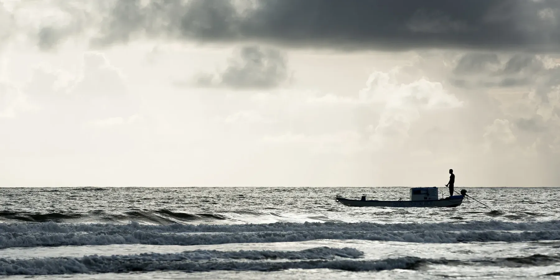 Embarcação solitária em mar aberto sob céu nublado no sul da Bahia, território de pesca artesanal