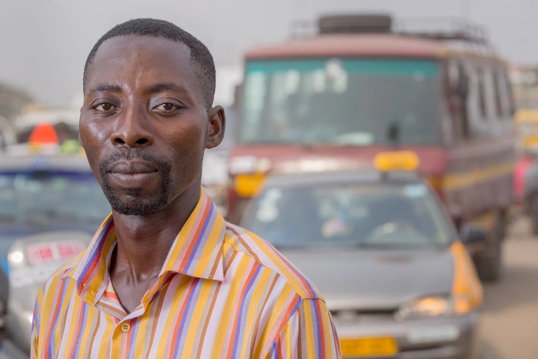 Pessoa em Acra, Gana, no meio da rua junto a obras viárias, rotatória e viadutos