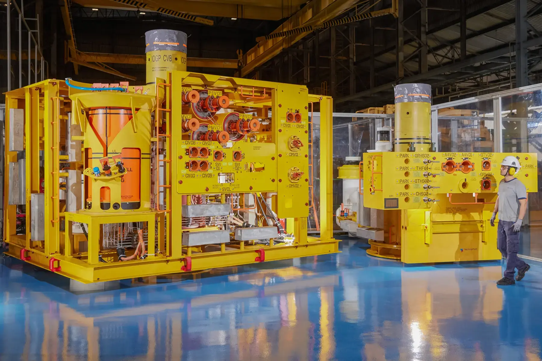 Equipamento industrial composto por duas peças que formam uma ANM (Árvore de Natal Molhada), com colaborador ao lado para escala