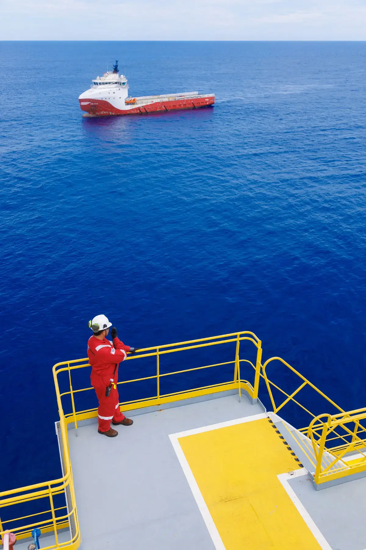 Colaborador em operação offshore comunica-se via rádio com embarcação de apoio próxima à plataforma