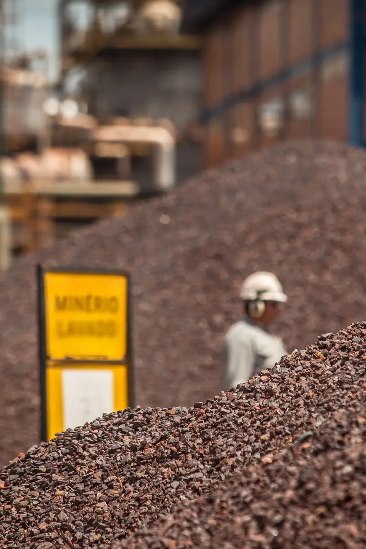 Pilha de minério lavado em unidade industrial de mineração no interior do Maranhão, com colaborador ao fundo