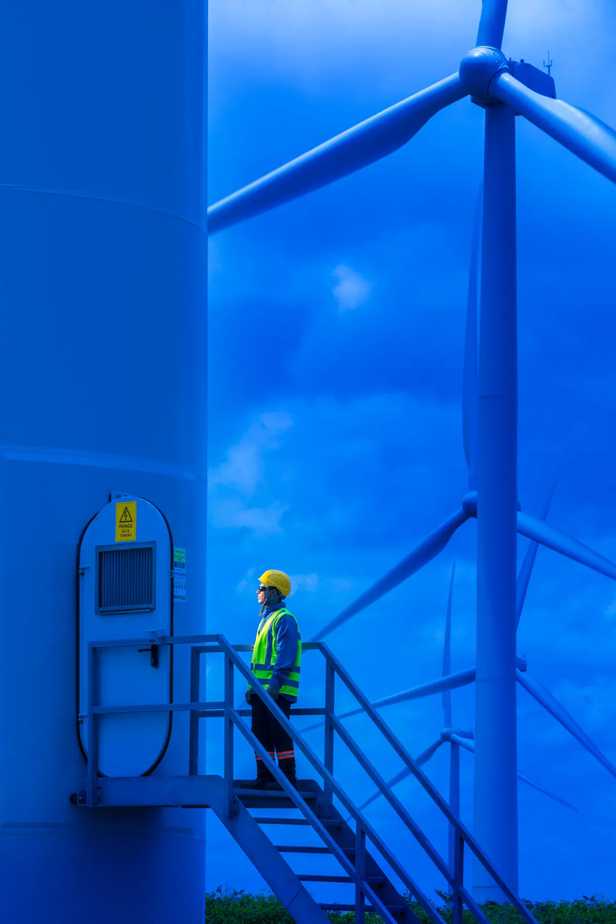 Colaborador realiza inspeção técnica em turbina do Complexo Eólico de Riachão, Ceará, com outras turbinas ao fundo