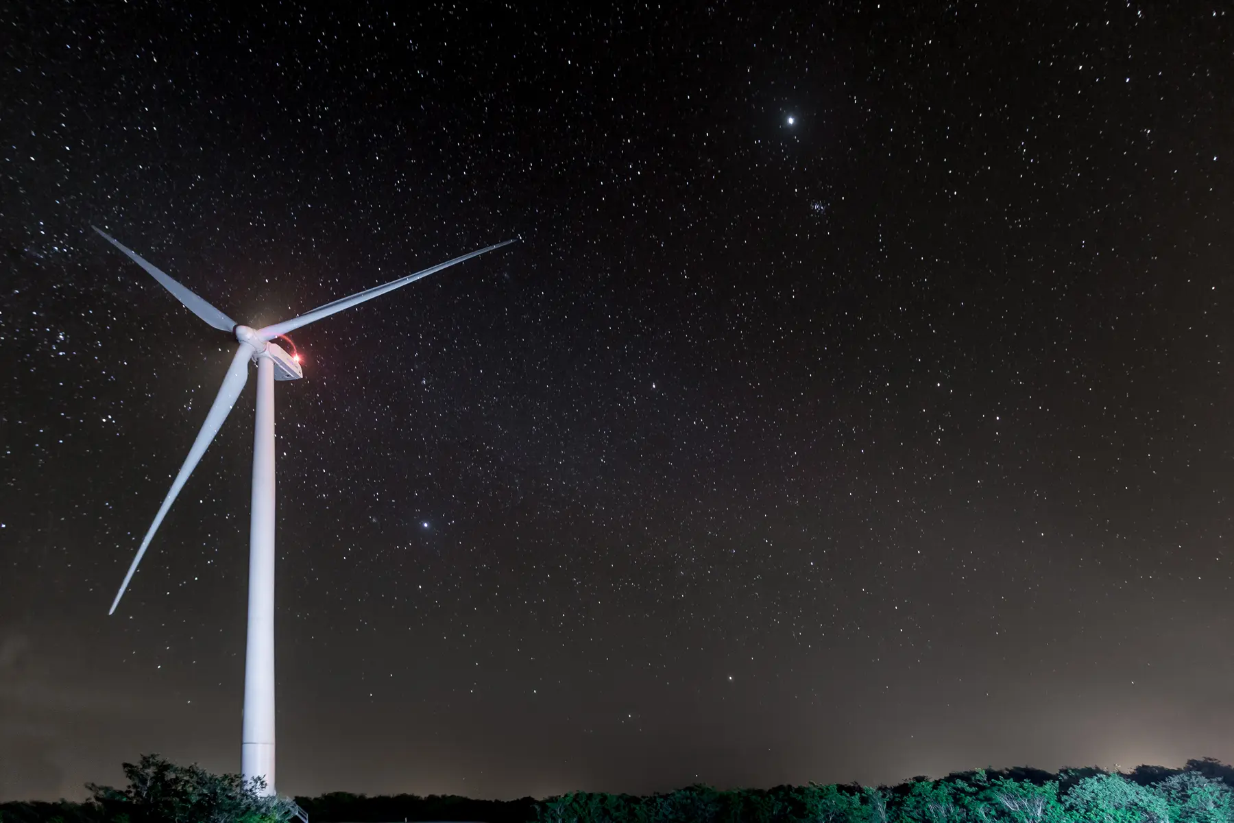 Turbina eólica iluminada à noite no Complexo de Riachão, Ceará, com céu estrelado ao fundo