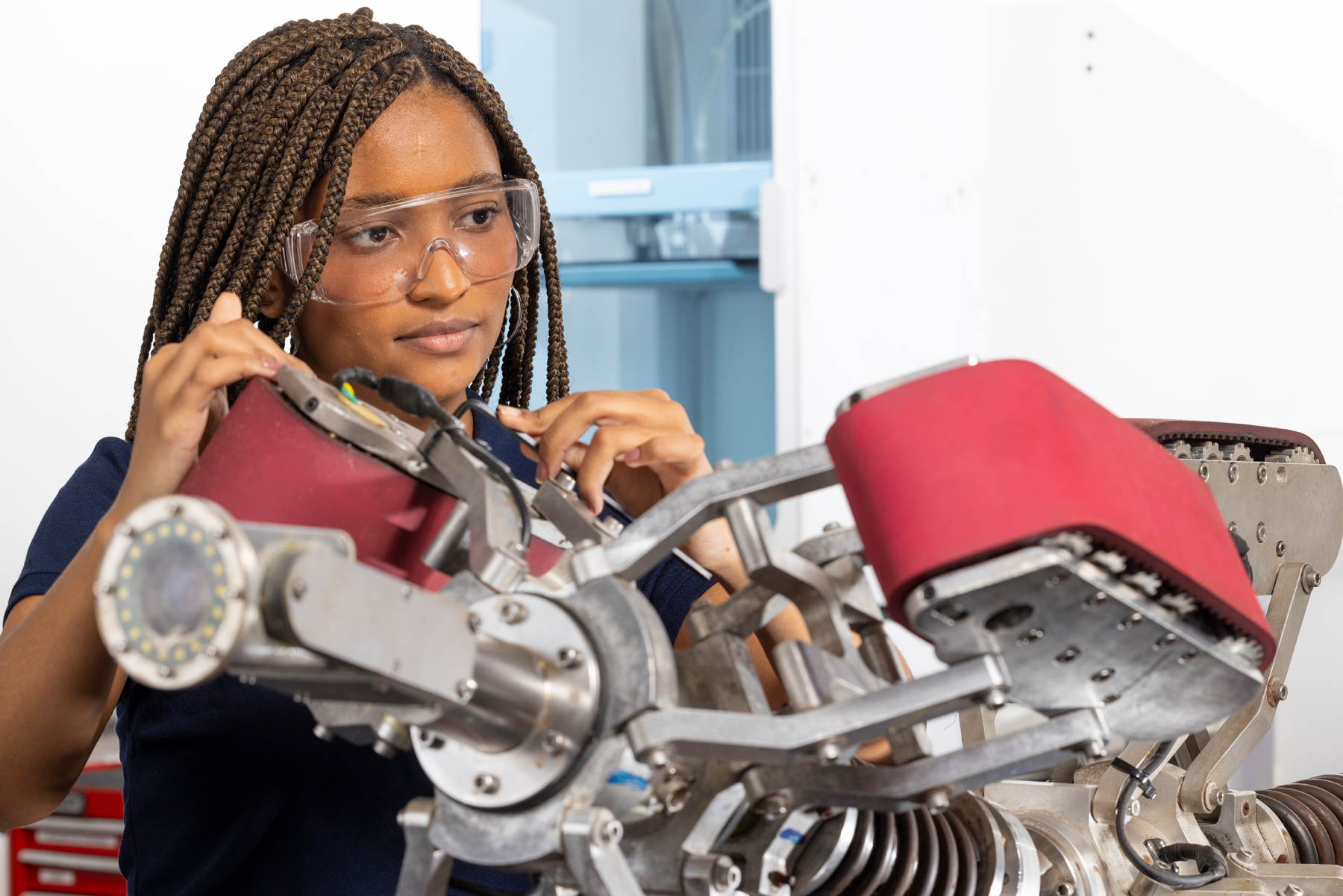 Pessoa montando máquina robótica com componentes metálicos e acolchoados em ambiente técnico