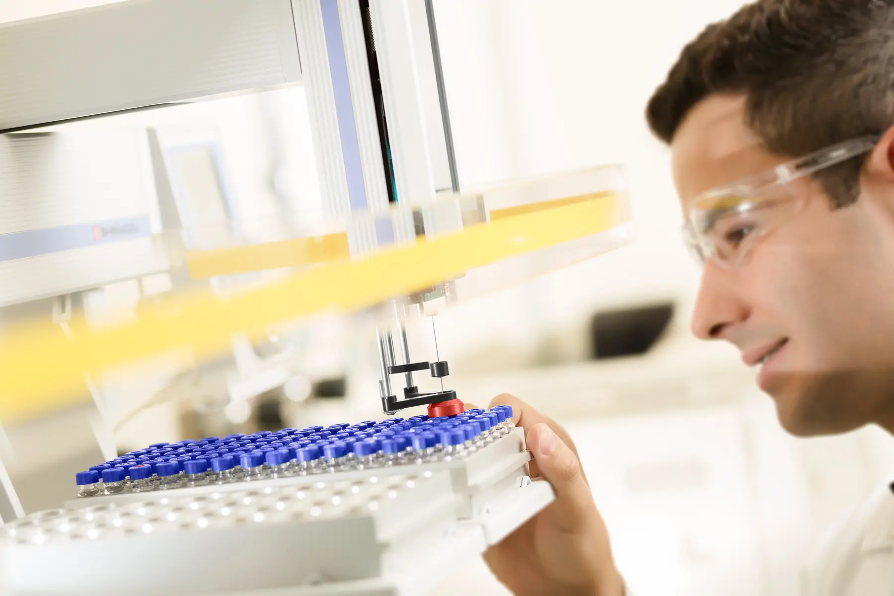 Braço robótico manipulando frascos em ambiente laboratorial automatizado com controle estéril e técnico.