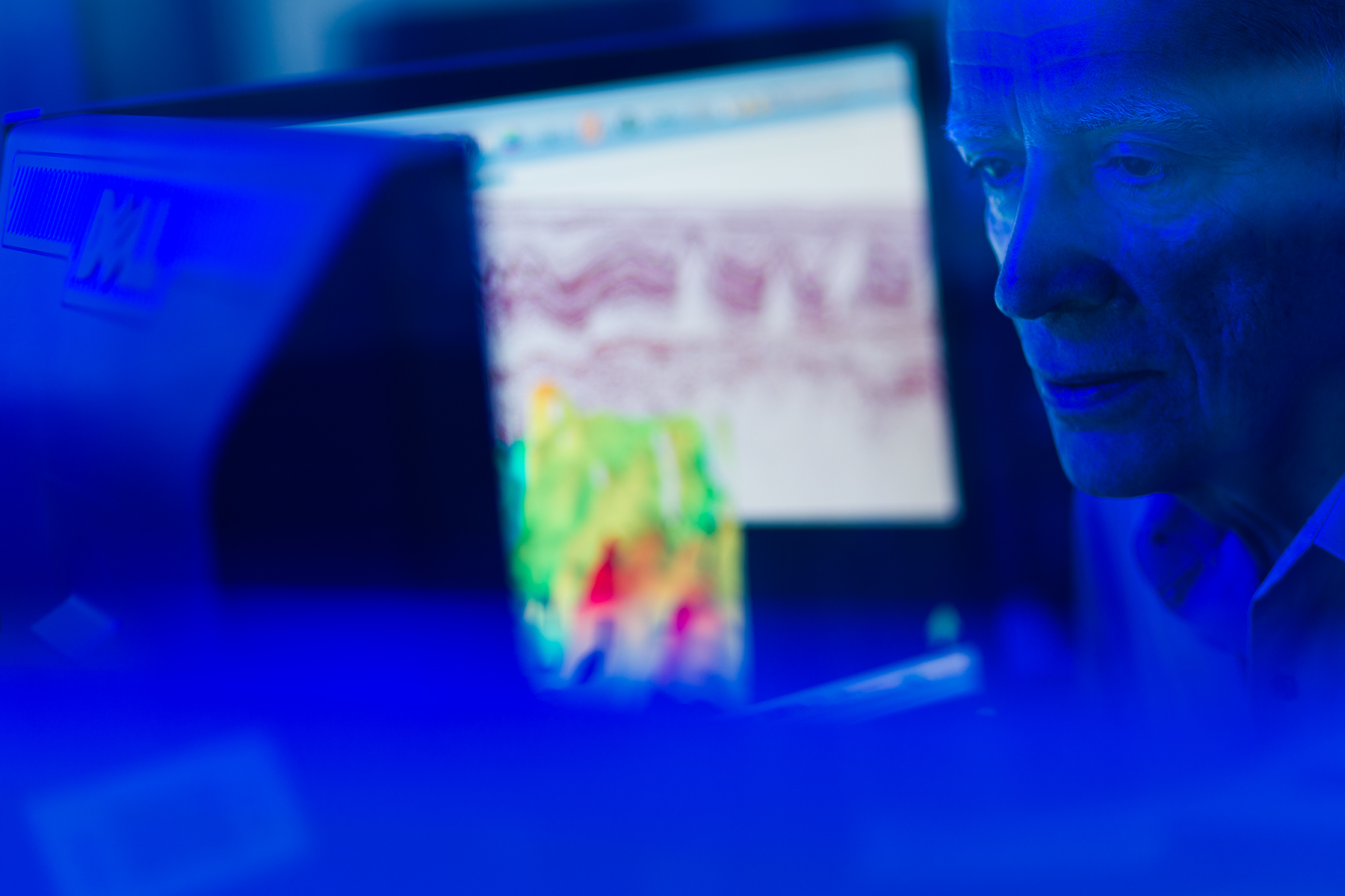 Pessoa analisando tela com padrões gráficos e mapa de calor em ambiente técnico azul